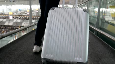 Nahaufnahme-der-Frau-zu-Fuß-mit-Trolley-Koffer-am-Flughafen.-Menschen-und-Lebensweisen-Konzept.-Rückansicht-und-niedrigen-Winkel