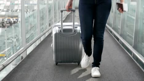 Nahaufnahme-der-Frau-zu-Fuß-mit-Trolley-Koffer-am-Flughafen.-Menschen-und-Lebensweisen-Konzept.-Vorderansicht-und-niedrigen-Winkel