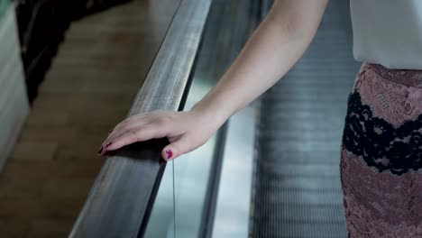 woman-rides-on-an-escalator-holding-onto-a-railing