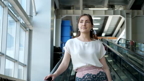 young-woman-rides-on-an-escalator,-holding-onto-a-railing