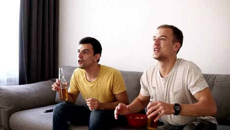 Dos-excitaron-a-hombres-adultos-bebiendo-cerveza-y-viendo-el-partido-de-fútbol-indoor-en-la-tv.-Celebrando-la-victoria,-gritando,-dando-cinco-de-alto.-Cierre-para-arriba