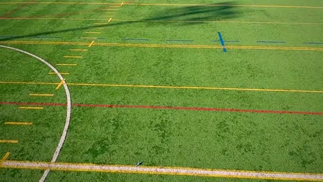 Volando-sobre-un-campo-de-fútbol-americano-de-síntesis-al-aire-libre