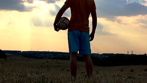 man-playing-with-a-ball-in-a-field-at-sunset,-man-playing-football-at-dawn