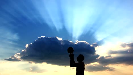 Silhouette-Mann-spielen-Fußball-auf-einem-Hintergrund-von-schöne-Wolken-bei-Sonnenuntergang