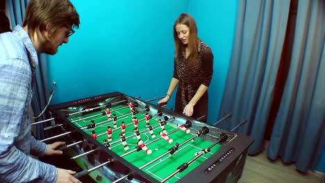 Beautiful-girl-young-guy-playing-table-soccer,-chatting-on-date