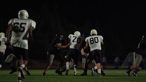 A-football-player-fights-his-way-down-the-field-toward-the-end-zone-at-night