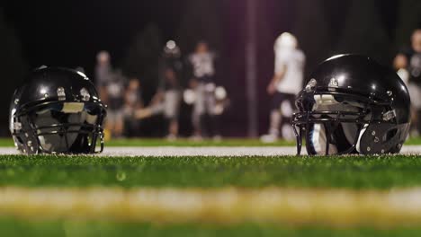 A-football-rolls-by-in-a-close-up-of-two-football-helmets-on-the-field