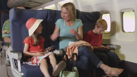 Mother-buckling-her-children-into-seats-on-plane