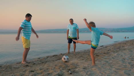 Männer-und-Junge-spielt-Fußball-am-Strand