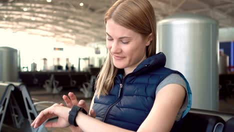 Schöne-Frau-mit-Smartwatch-im-Flughafen.-Surfen-Internet,-kommunizieren-mit-ihren-Freunden