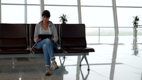 Woman-using-a-digital-tablet-in-airport-waiting-area