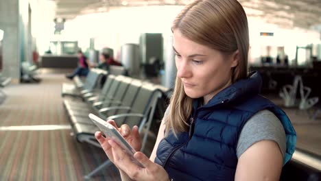 Schöne-Frau-mit-Smartwatch-und-Smartphone-in-Flughafen.-Empfang-einer-Nachricht-von-Freund