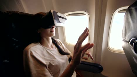 Junge-Touristen-Frau-entspannen-und-mit-VR-Kopfhörer-für-Smartphone-während-des-Fluges-im-Flugzeug
