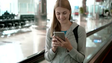 Woman-using-travolator-in-airport-terminal.-Waiting-for-flight.-Using-her-smartphone,-browsing