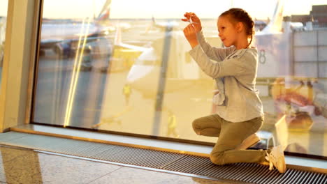 Adorable-niñita-jugando-con-aeroplano-modelo-pequeño-en-el-aeropuerto-a-la-espera-de-embarque.-Concepto-de-vuelo-y-avión.