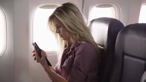 Young-woman-using-digital-tablet-on-airplane-flight