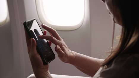 Closeup-of-woman-using-cell-phone-on-airplane