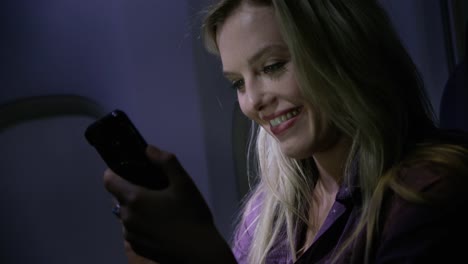 Closeup-of-young-woman-using-cell-phone-on-airplane