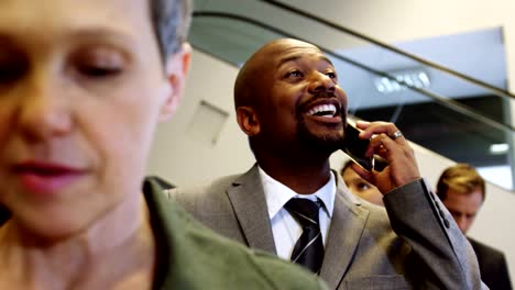 Businessman-talking-on-mobile-phone-while-standing-in-a-line