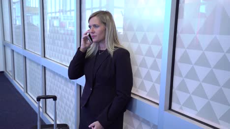 Business-woman-using-cell-phone-at-airport