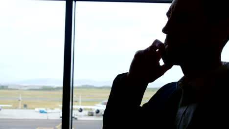 Businessman-talking-on-mobile-phone-at-airport