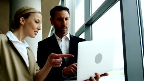 Businessman-and-woman-discussing-on-laptop