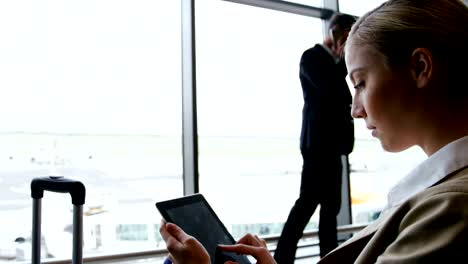 Businesswoman-using-digital-tablet-and-smiling-at-airport