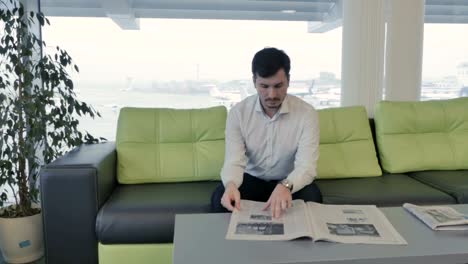 Businessman-wait-boarding-on-plane-and-reads-newspaper-in-lounge-hall