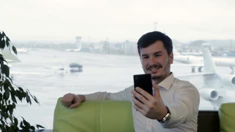 Hombre-de-negocios-toma-un-selfie-en-el-pasillo-de-salón-del-aeropuerto