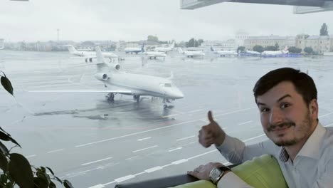 Hombre-lindo-en-el-aeropuerto-muestra-el-pulgar-hacia-arriba-a-la-cámara