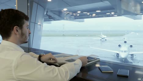 Young-businessman-read-magazine-in-airport-during-waiting-boarding-on-plane