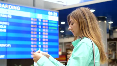 Mujer-joven-se-ve-en-el-tablero-de-información-de-las-salidas-en-el-aeropuerto.