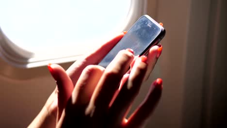 Primer-plano-de-la-mano-de-la-mujer-con-el-teléfono,-sentado-en-la-ventana-del-avión