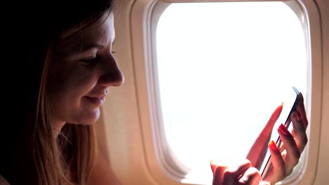 Una-hermosa-mujer-utiliza-el-teléfono,-sentado-en-la-ventana-del-avión