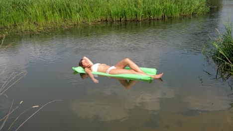 Young-Woman-In-White-Swimsuit-Sunbathing-Laying-On-Mattress-In-The-Water