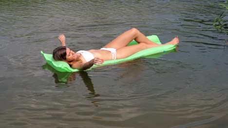 Young-Tanned-Woman-In-A-White-Bikini-Floating-In-The-River-On-The-Mattress.