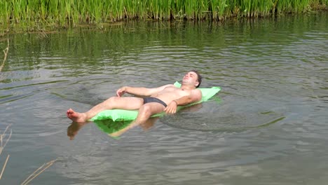 Den-Mann-ruhen-In-den-heißen-Sommertag-im-Fluss-schwimmen-auf-der-Matratze.