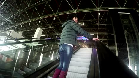 Attractive-female-on-airport-departure-escalator-wave-hand-farewell