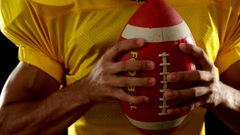 American-football-player-holding-ball-against-black-background-4k