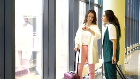 Mujeres-jóvenes-con-equipaje-en-el-aeropuerto-internacional-de-caminar-con-su-equipaje.-Pasajeros-de-líneas-aéreas-en-un-salón-del-aeropuerto-esperando-el-avión-de-vuelo