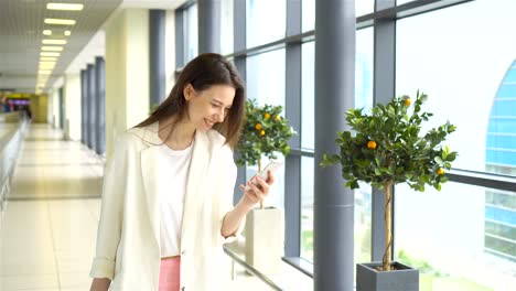 Muchacha-de-turista-con-smartphone-en-el-aeropuerto-internacional.-Pasajeros-de-la-aerolínea-en-un-salón-del-aeropuerto-esperando-el-avión-de-vuelo