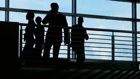 Silhouette-der-Businessmanager-im-Flughafen-mit-mobilen