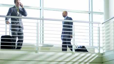 Positive-businessman-using-smartphone-technology-on-airport-atrium