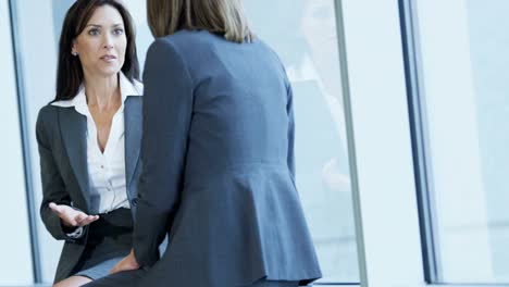 Caucasian-American-female-colleagues-meeting-in-airport-lounge