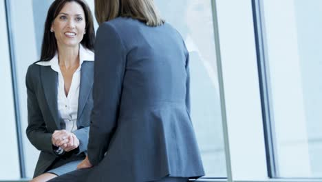 Caucasian-female-business-commuters-talking-in-airport-lounge