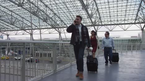 Businessman-walking-and-talking-on-cell-phone-at-airport