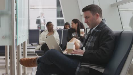 Businessman-working-on-laptop-at-airport