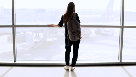 Junge-Frau-mit-Rucksack-in-der-Nähe-von-terminal-Fenster.-Kaukasische-weibliche-Touristen-mit-Smartphone-in-Flughafen-Lounge.-Reisen.-4K