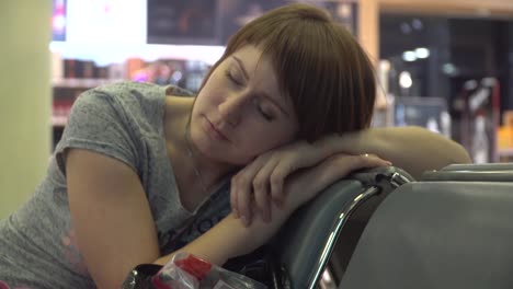 woman-sleeping-at-the-airport-waiting-area.-flight-delay