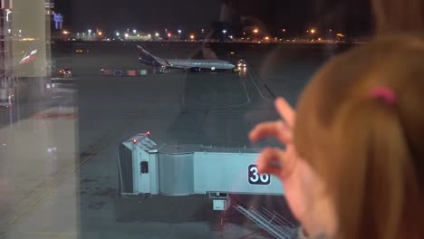 A-little-girl-with-mom-looks-at-the-planes-at-the-airport